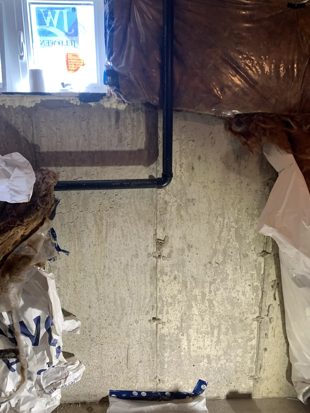 Foundation wall cold joint with moisture staining in a basement under renovation, before crack injection