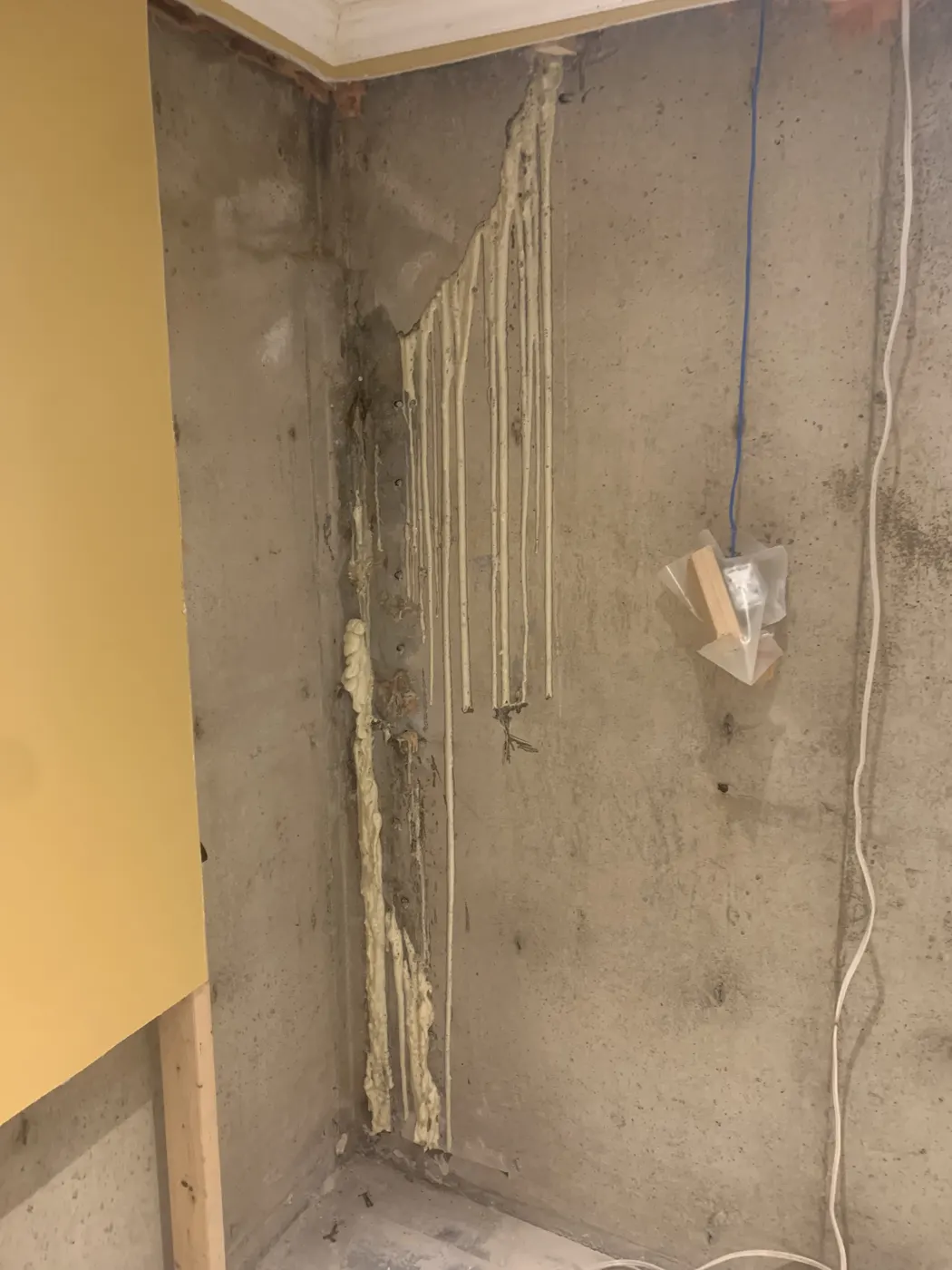 Basement corner cold joint with seepage staining on a poured concrete wall before crack injection