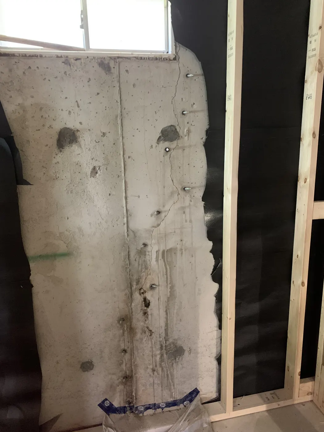 Metal injection ports installed along a stair-step foundation crack in a parged basement wall, ready for injection